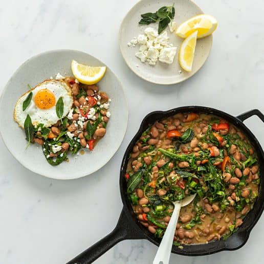 Pan of borlotti beans next to a plate of beans, topped with a fried egg, feta and lemon.