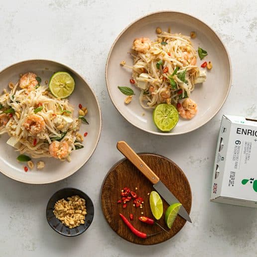 Two plates of prawn noodles alongside a pate of chillis and a box of Enriched Eggs.