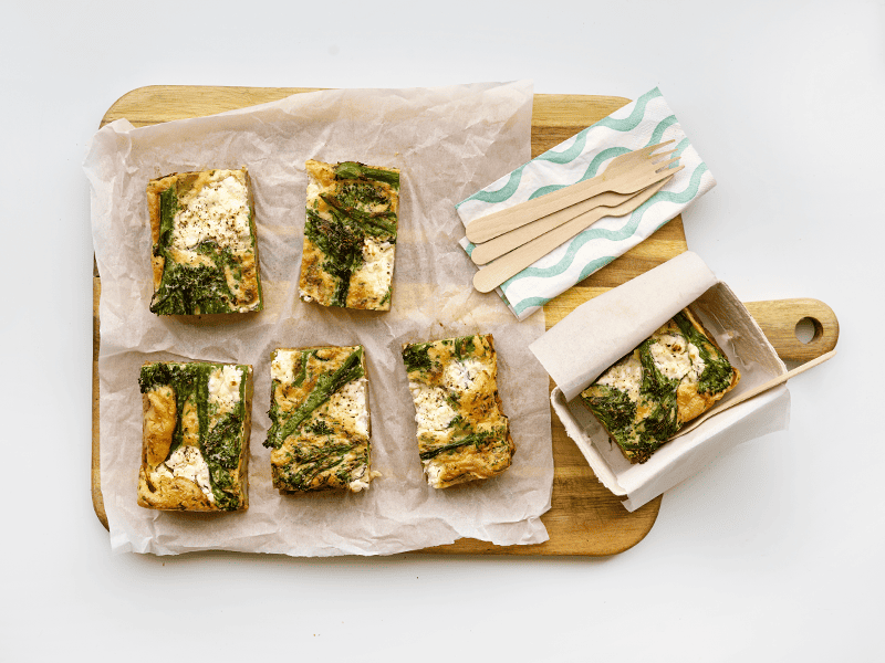 Six slices of Enriched eggs picnic frittata on a wooden chopping board.