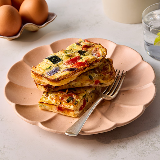 A stack of veg-packed frittatas sit on a pink, leaf-shaped plate